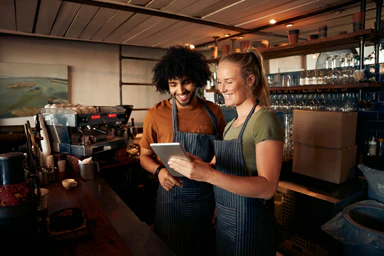 Zwei Baristas schauen in ein Notizbuch.
