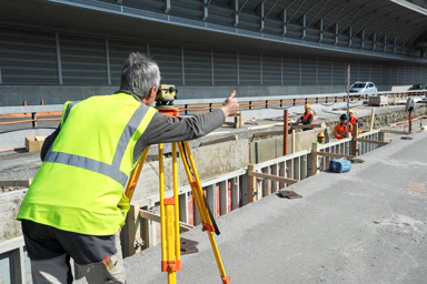 Eine Person nimmt auf einer Baustelle Vermessungen vor.