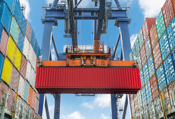 Ein Kran verlädt Container in einem Hafen.