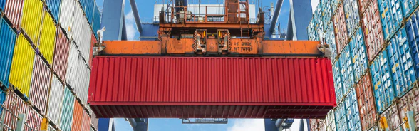 Ein Kran verlädt Container in einem Hafen.