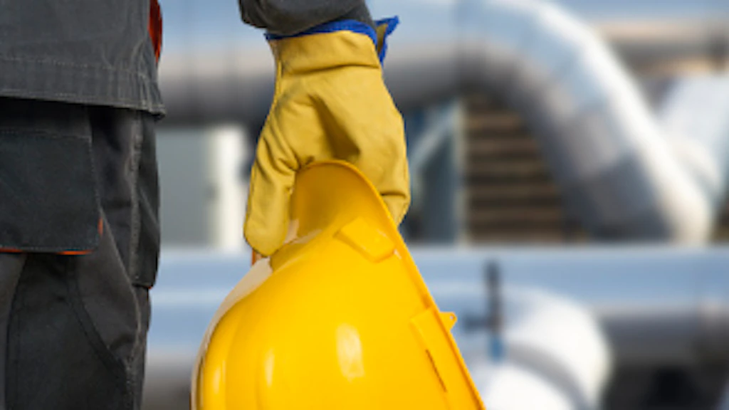 A man holds a construction helmet in his right hand