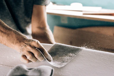 A person sanding a wooden panel.