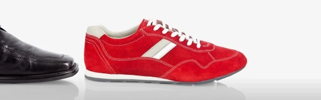 Red trainer lying in front of a black leather shoe