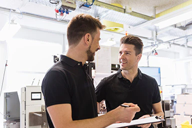 Two men talking in a factory.