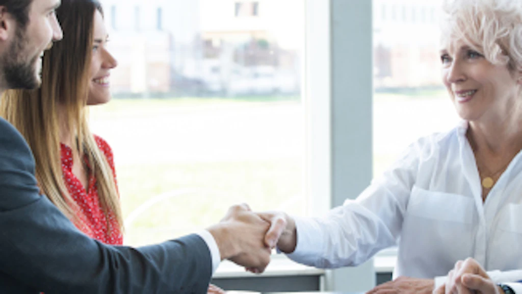 A man and a woman shake hands during a (work) meeting