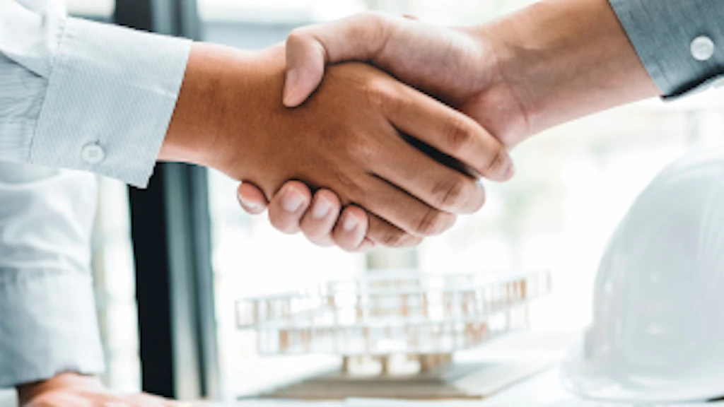 Two men in suits shake hands.