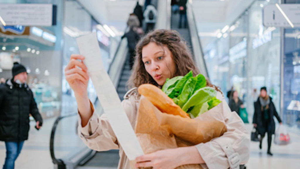A woman in a supermarket with a long receipt.