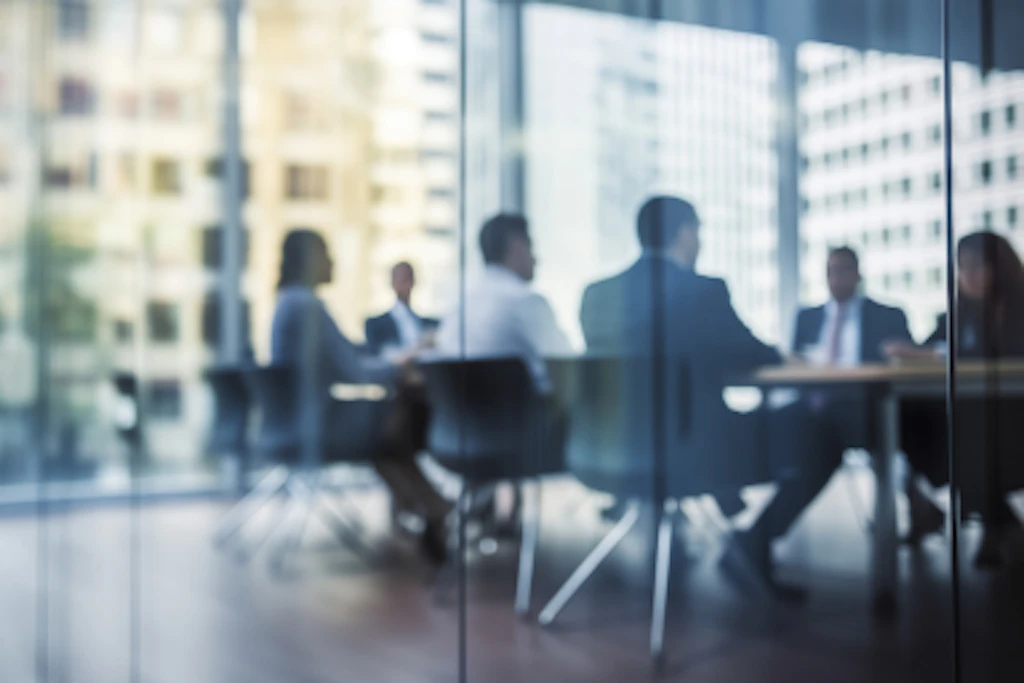 People in a meeting behind a glass window.