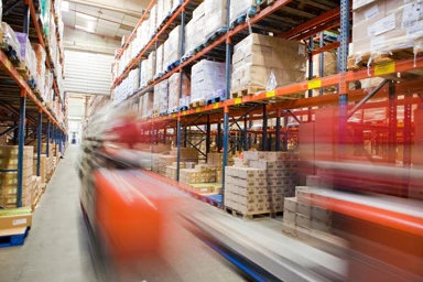 Industrial warehouse with shelves of packaged goods.
