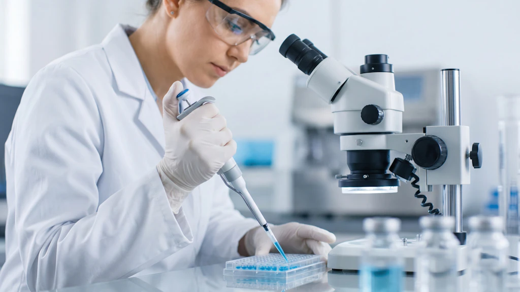 A scientist filling test tubes while working at a microscope.