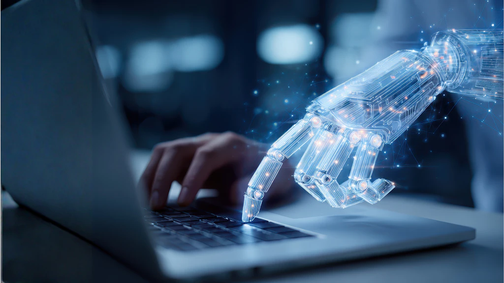A human hand and a robotic hand are typing away on a computer keyboard.