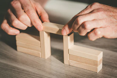 A person stacks small wooden rectangles.