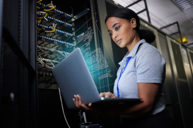 A woman with a computer in a data centre.
