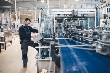 Un homme fait des réglages sur une chaîne de production.