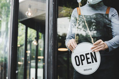 Une personne ouvre sa boutique avec le sigle "open".