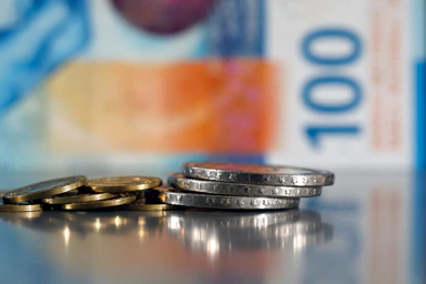Des pièces de cinq francs et cinq centimes devant un billet de cent.
