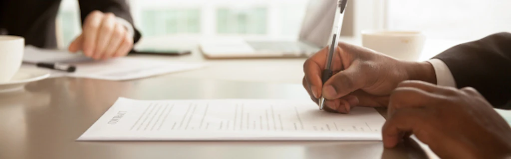 Un homme complète un document à l'aide d'un stylo.