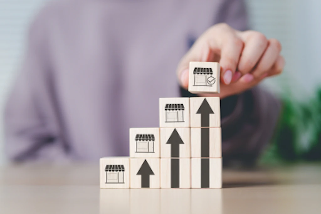 Des cubes en bois avec des flèches montantes et des pictogrammes de marchés.