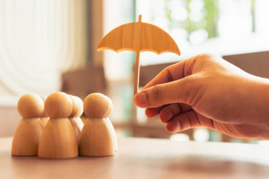 Des bonhommes en bois et une main qui tient un parapluie en bois.