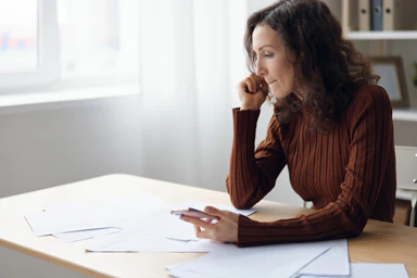 Une femme assise à un bureau devant une pile de feuilles.