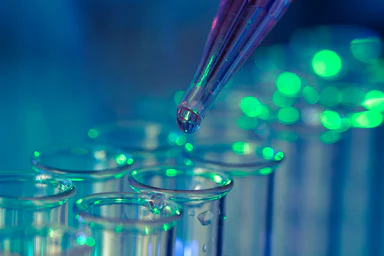Une pipette de laboratoire verse un liquide dans des tubes à essai.