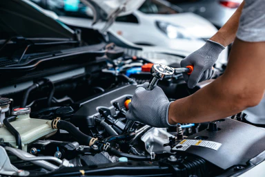 Un employé répare le moteur d’une voiture.