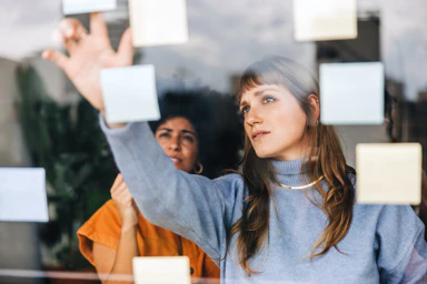 Deux femmes devant une fenêtre avec des post-its.
