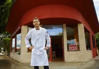 Patron de restaurant devant son établissement