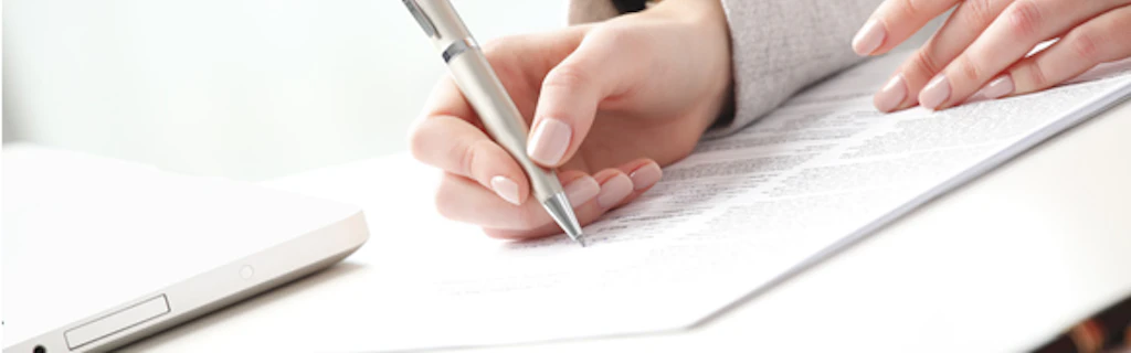 Primo piano sulle mani di una donna nell'atto di compilare un documento.