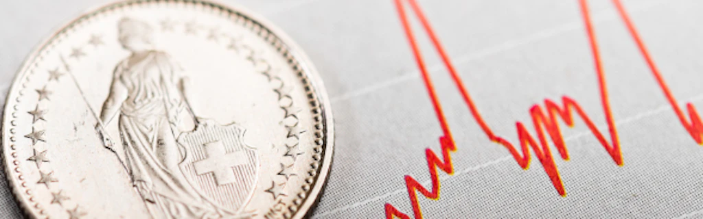 Una moneta svizzera, sullo sfondo un grafico delle quotazioni di borsa.