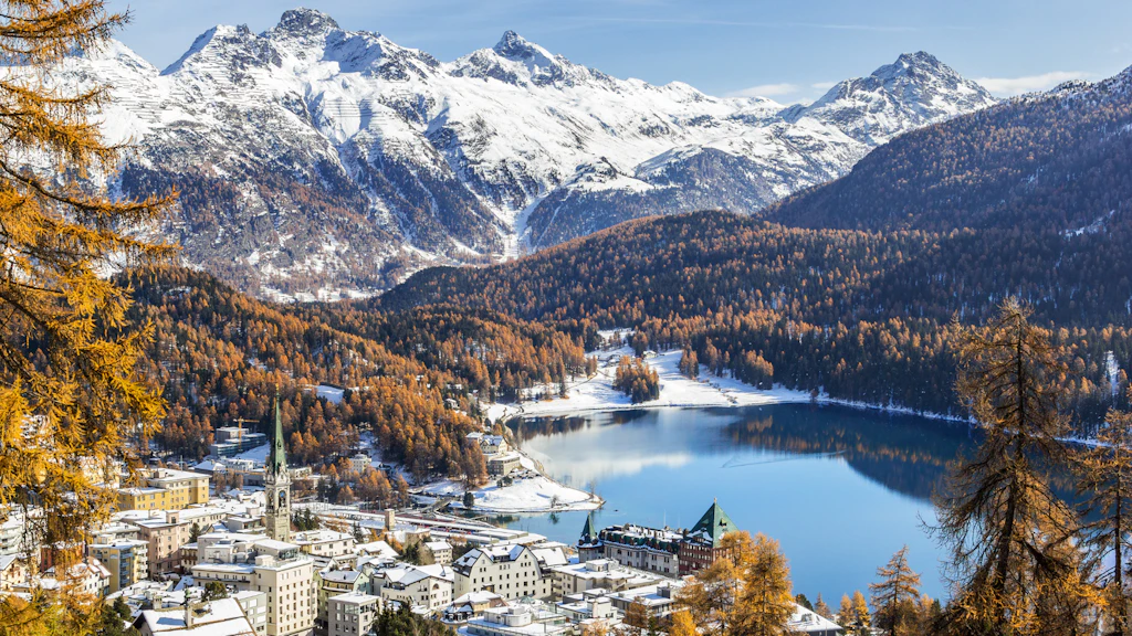 Montagne e villaggi innevati, boschi autunnali, lago cristallino