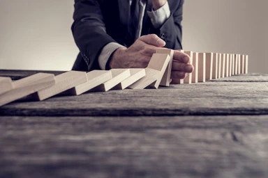 Una persona ferma l'effetto domino con la mano.