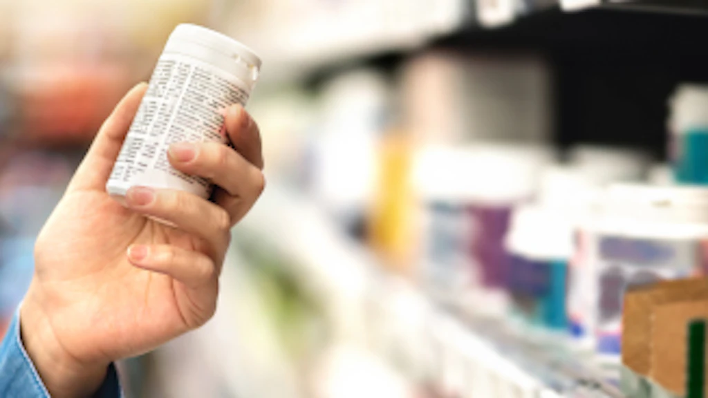 Un consumatore prende una scatola di medicinali dallo scaffale di un negozio.
