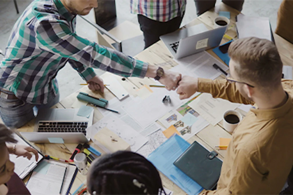 due ragazzi si salutano pugno contro pugno sopra una postazione di lavoro.